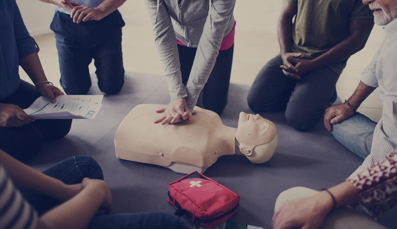 group of people learning CPR with a training dummy.
